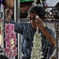 Senior woman holding garlands in store