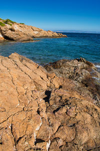 Scenic view of rocks on beach against clear blue sky