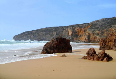 Rock formation on beach against sky