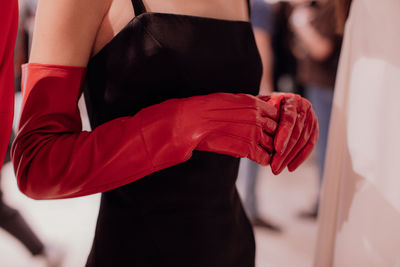 Female hands in a leather stylish red gloves and black classy dress. fashion shot.