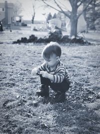 Full length of cute boy crouching on land