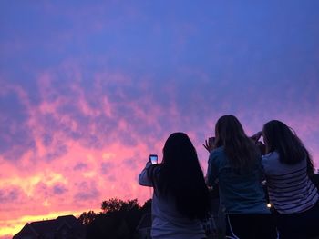 Rear view of female friends photographing sunset