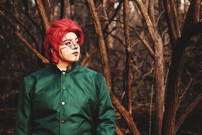 Portrait of young woman standing against plants