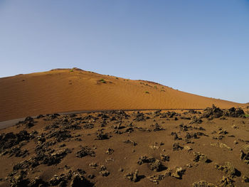 Sand dunes in desert against clear blue sky