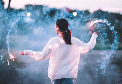 Rear view of woman holding sparklers