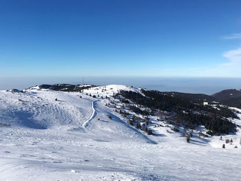 Scenic view of snow covered landscape against clear blue sky