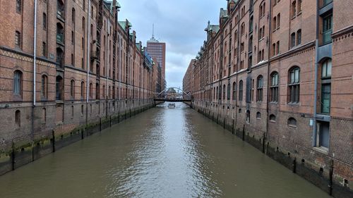 Canal amidst buildings in city against sky