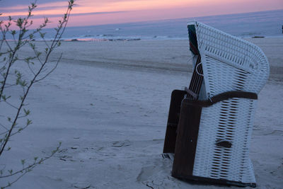 Lifeguard hut on beach against sky during sunset