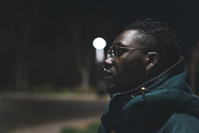 Close-up of thoughtful young man looking away at night