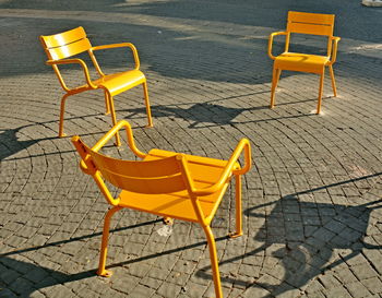 High angle view of empty chairs and table at sidewalk