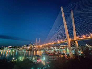 Illuminated bridge over river in city at night