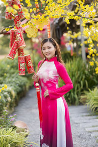 Full length of woman standing against pink wall