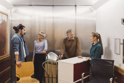 Multi-ethnic male and female business people with office equipment in elevator