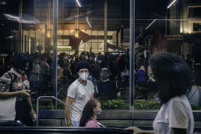 People standing on street seen through glass window