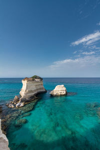 Scenic view of light blue and crystal clear sea against white clouds sky