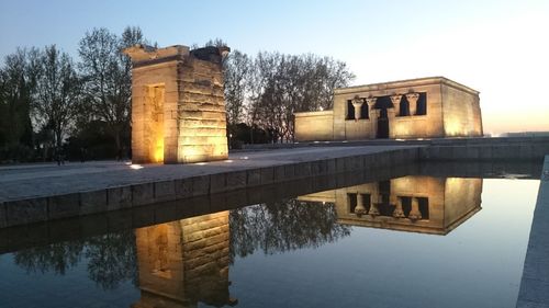 Reflection of building in lake against sky at dusk