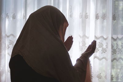 Side view of woman holding window at home