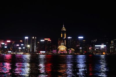 Illuminated buildings by river at night