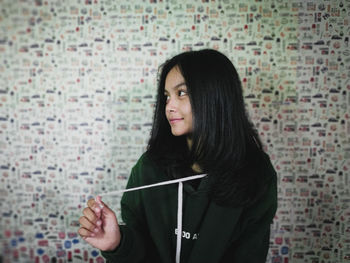 Young woman standing against wall