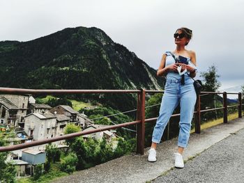 Full length of woman looking away while standing by railing against mountain