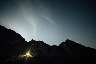 Light glowing on mountain against sky at night