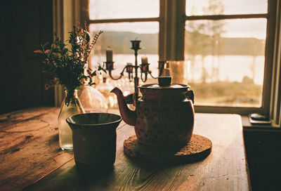 Close-up of tea cup on wooden table against window at home