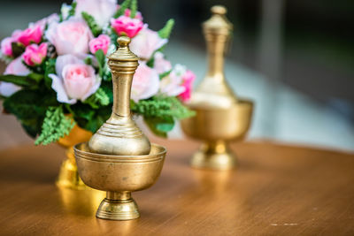 Golden flagons for pouring water of dedication with bouquet, thai tradition, buddhism