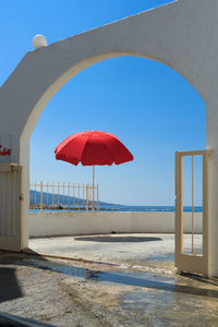 Red umbrella on beach against clear blue sky