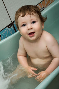 Close-up portrait of baby boy sitting in bathtub