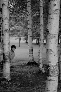 Side view of woman standing by trees in forest