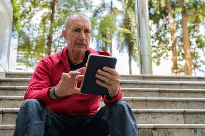 Young man using mobile phone while sitting outdoors