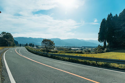 Road by trees against sky