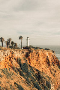 Lighthouse by sea against sky