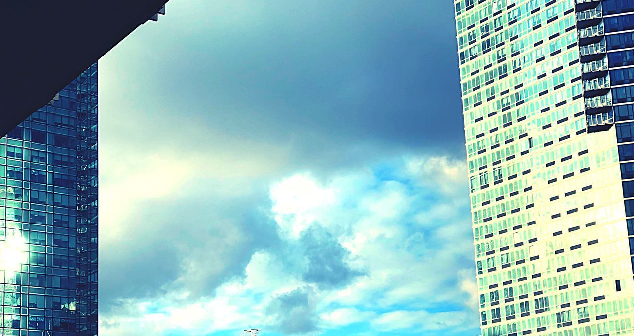 LOW ANGLE VIEW OF MODERN GLASS BUILDING AGAINST SKY