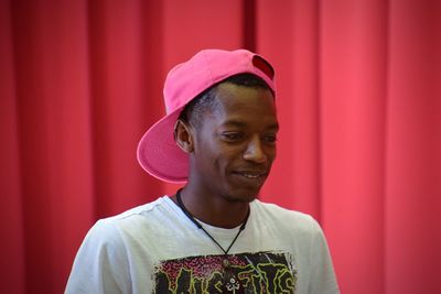 Portrait of young man standing against red curtain