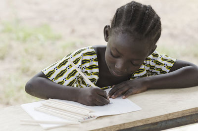 Close-up of girl writing in book