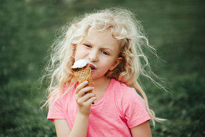 Girl eating licking ice cream from waffle cone. child eating tasty sweet cold summer food outdoor. 