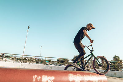 Side view of man riding bicycle against clear sky