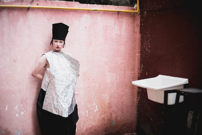 Portrait of senior woman standing against wall