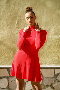 Portrait of young woman standing against wall