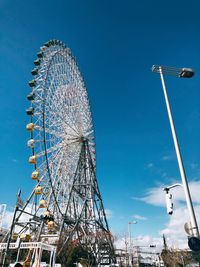 Low angle view of ferris wheel against blue sky
