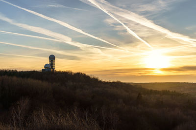 Lighthouse on field against sky during sunset