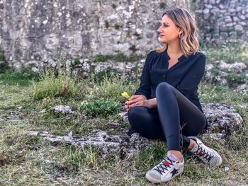 Full length of young woman sitting on field