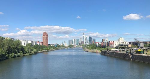 City by river and buildings against sky