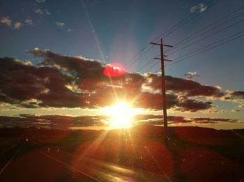 Low angle view of electricity pylon against sky during sunset