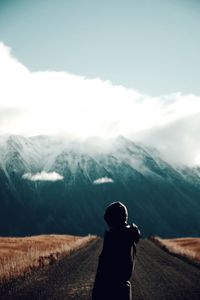 Rear view of woman standing on snowcapped mountain against sky