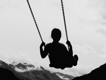 Rear view of girl sitting on swing