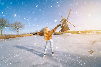 Rear view of person on snow covered field against sky