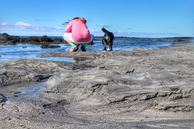 Rear view of woman with dog on beach