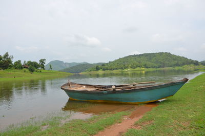 Rowboat moored at lake against sky
